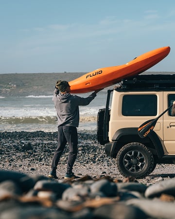 Dometic gear in use: loading a kayak onto a roof rack at the coast